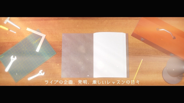 作業台の上にノートが開かれていて、「ライブの企画、発明、厳しいレッスンの日々」というテロップが付いているスクリーンショット